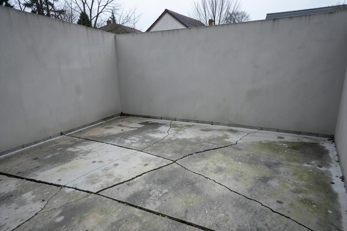 Neglected walled concrete yard with cracked slabs before the terrace concept